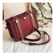 Load the image into the gallery viewer, Woman's shoulder bag in burgundy color with gold chain handle, small studs and zip closure
