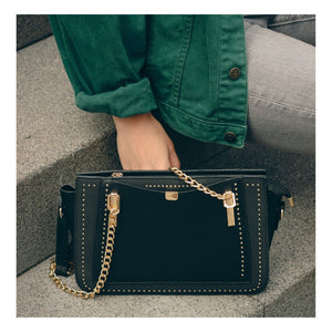 Black shoulder bag for women with golden chain handle, small rivets and zipper